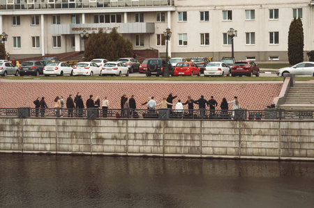 Group of students holds class on river embankment near the university building with parking lot....