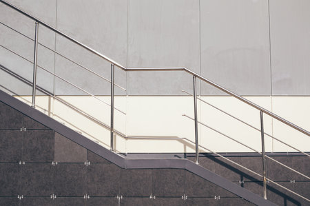 Damaged metal stair railing with hole on background of wall, tiles and granite. Diagonal and straight linesの写真素材