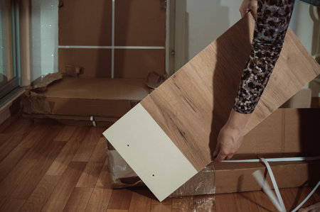 Unpacking furniture. Removing furniture from a cardboard box. Locker door in female handsの写真素材