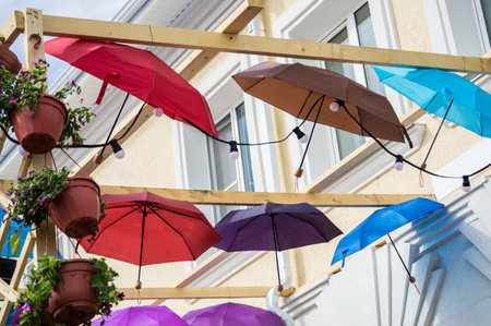 Rows of colorful umbrellas floating in the air. City street decoration on a rainy autumn dayの写真素材