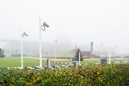 Two video surveillance cameras on poles, and checkpoint against the background of the city in a very...