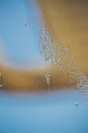 Blue-yellow background of wet glass with raindrops, splashes and jets. Color blurred abstractionの写真素材