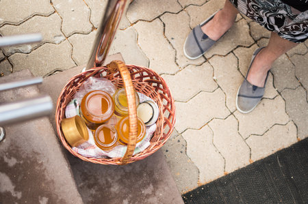 Fresh bee honey, dark brown and light golden, in glass jars in basket, at agricultural fair. Fresh harvest and healthy nutrition with eco-productsの写真素材