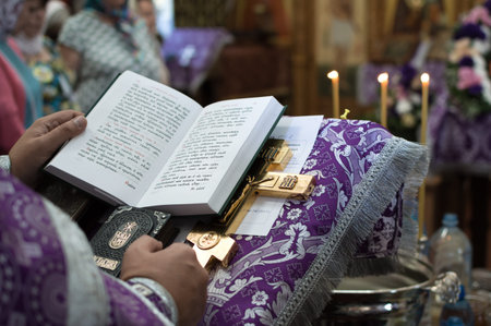 The hands of a priest with a prayer book and a cross at a divine service in the Orthodox Church