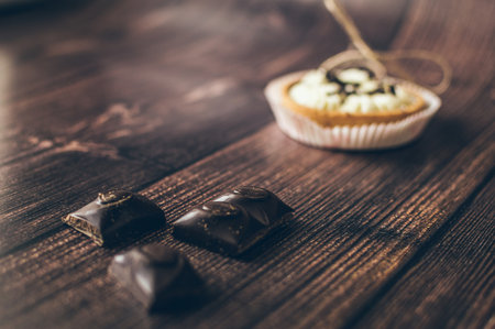 Tartlets with buttercream and pieces of bitter chocolate on a dark brown diagonal background, copy spaceの写真素材