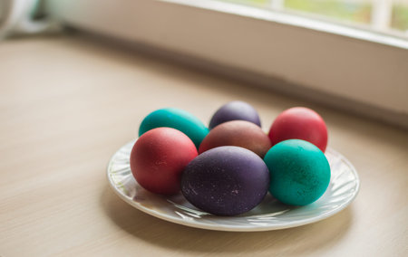 Seven colorful Easter eggs on a plate on a light beige background, copy space