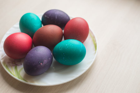 Seven colorful Easter eggs on a plate on a light beige background, copy spaceの写真素材