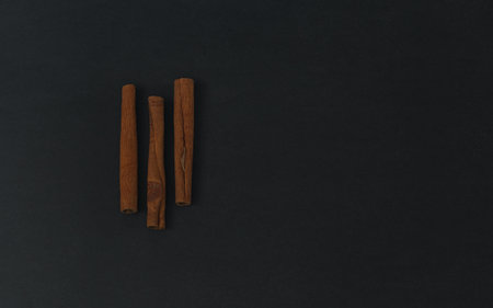 Cinnamon sticks on black background, flatlay in dark keyの写真素材