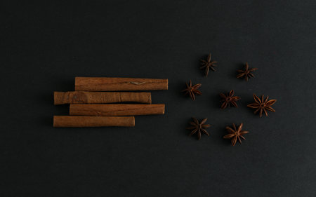 Cinnamon sticks and anise stars flatlay on black backgroundの写真素材