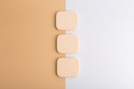 Three make up sponges on beige and pink backgroundの写真素材