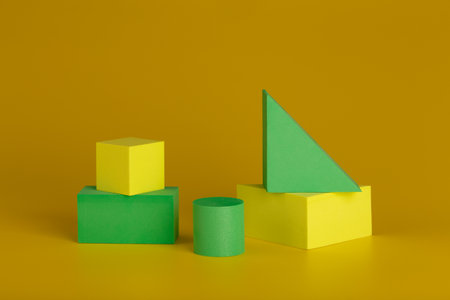Duotone geometric still life with yellow and green figures against dark yellow backgroundの写真素材