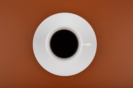 Top view of white coffee cup on a table against brown backgroundの写真素材