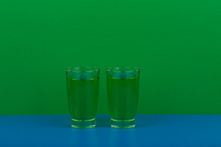 Two green drinks on blue table against green background with space for textの写真素材