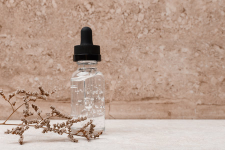 Skin serum in transparent bottle with black cap against marble background with space for textの写真素材