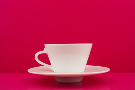 White ceramic coffee cup on pink table against pink background with copy spaceの写真素材