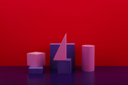 Abstract geometric composition with purple figures on purple shiny table against red background with...