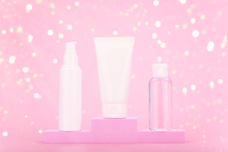 Three beauty products on pink winner pedestal against pink background with bokeh. Concept of gifts and holidaysの写真素材