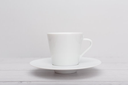 Selective focus, white tea or coffee cup on wooden table against white blurry backgroundの写真素材