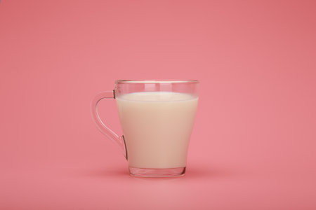 Transparent cup with milk against pink background with copy spaceの写真素材