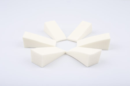 Triangle shaped make up sponges arranged in a circle on white background. Concept of visage and beauty blendersの写真素材