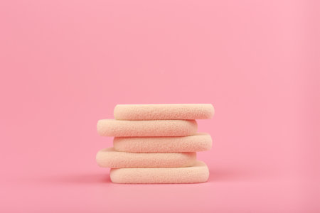 Horizontal minimalistic still life with stack of beige make up sponges on pink background with copy space.の写真素材