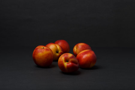 Bunch of nectarines on black table against black background with copy spaceの写真素材