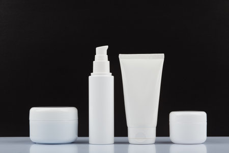 Cream tubes on white glossy table against black background. Concept of male skincare and beauty routineの写真素材
