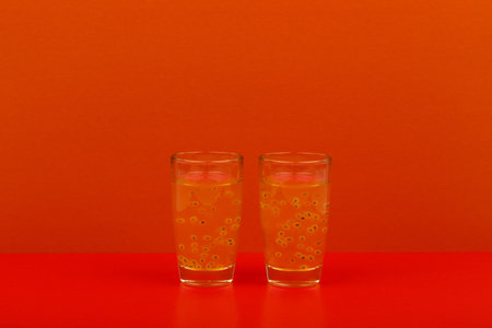 Two shots with fruit alcohol drink on red table against red background with copy space. Concept of...