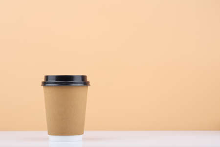 Disposable coffee cup on white table against light beige background with copy spaceの写真素材