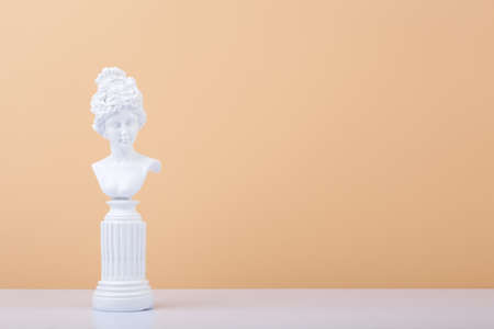 White gypsum statue on white table against beige background with copy spaceの写真素材