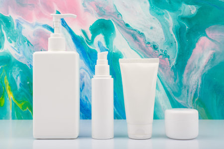 Body cream, face cream, face lotion and under eye cream on white table against blue marbled backgroundの写真素材