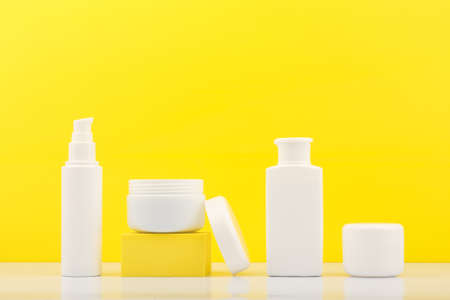 Set of cosmetic bottles with products for skin care against bright yellow backgroundの写真素材