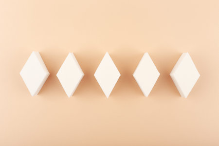Top view of diamond shape make up sponges against beige background