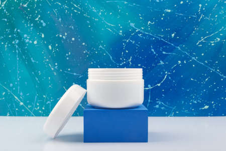 Night cream in white opened jar on blue podium against abstract blue backgroundの写真素材