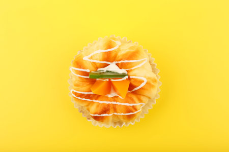 Top view of cupcake with pieces of peaches and kiwi fruit and cream against yellow background