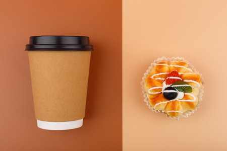 Top view of coffee or tea in brown cardboard cup with pastry against brown and beige backgroundの写真素材
