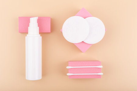 Foam or lotion for make up removing, cotton pads and cotton swabs on pink podiums against beige...
