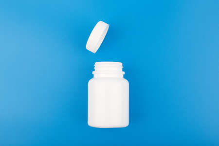 Top view of white opened medication bottle against blue backgroundの写真素材