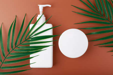 Cosmetic products for self tanning on brown background with palm leavesの写真素材