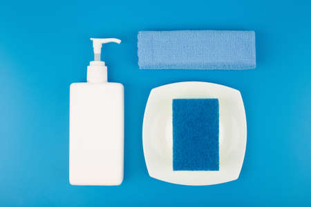 Detergent, dust cloth, cleaning sponge and white plate on blue backgroundの写真素材