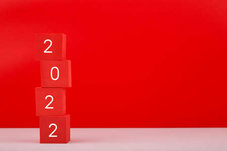 2022 Happy New Year red minimal trendy concept. Modern composition with red toy blocks with written 2022 numbers against red background with copy space.の写真素材