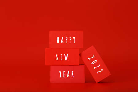 Happy New Year bright red minimal trendy concept. Modern composition with red and yellow toy blocks with written Happy New Year text against red background with copy space. Minimalistic postcardの写真素材