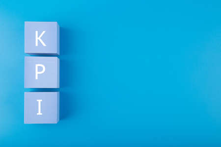Minimal modern business KPI concept. KPI letters on light blue cubes against dark blue background with copy space. High quality photoの写真素材
