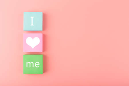 Trendy minimal I love me creative concept of self love and mental health or being single. Multicolored blocks with text against pastel pink background with copy spaceの写真素材
