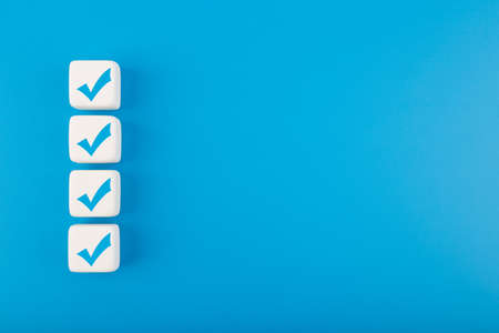 Four blue checkmarks on white cubes in a row against blue background with copy space. Concept of questionary, checklist, to do list, planning, business or verification. Modern elegant flat layの写真素材