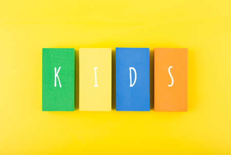 Word kids on colorful rectangles against bright yellow background. Concept of pre school, kindergarten, child care centerの写真素材