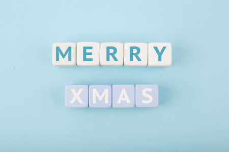 Merry Xmas minimal concept in light pastel blue colors. Handwritten text Merry Christmas on blue tablet against blue background. Modern trendy Merry Xmas conceptの写真素材