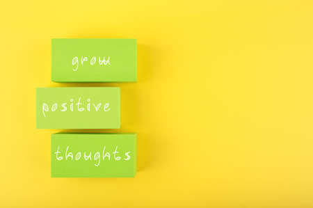 Positive affirmation, mental health or quote concept. Grow positive thoughts written on green rectangles on yellow background with copy space. Motivational text for inner pieceの写真素材