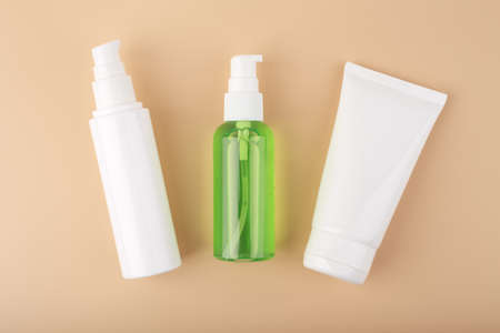 Cosmetic products in white unbranded tubes on pastel beige background. Set of face cream, lotion or gel and foam for daily skin cleaning, exfoliating, moisturizing and nourishing. Set of organic beauty productsの写真素材