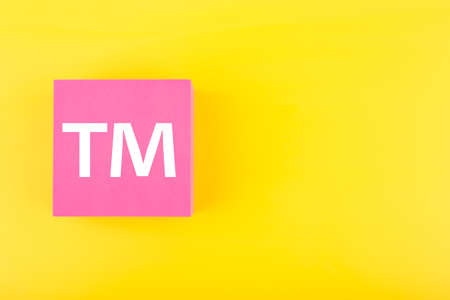 TM trademark sign on pink figure on yellow background with copy space. Concept of intellectual property registration and protectionの写真素材